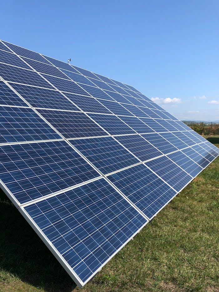 Solar panels in a green field on a sunny day, showcasing renewable energy in Tortona, Italy.